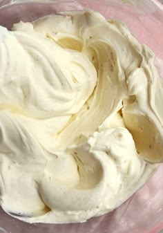 whipped cream in a glass bowl on top of a pink tablecloth with white trim