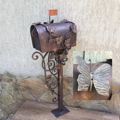 a metal mailbox with a butterfly decoration on it's side next to a stone wall