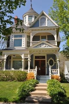 a large white house with blue trim on the front door and porch, surrounded by lush green grass