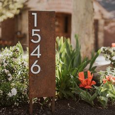 a house number sign in front of some flowers