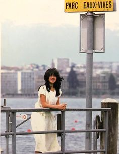 a woman standing on a pier next to a sign that says paris eau - vives