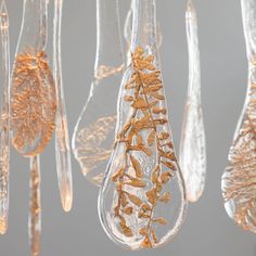 several glass ornaments hanging from the ceiling with gold leaf designs on them, all in different shapes and sizes