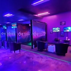 an indoor gaming room with purple lighting and black chairs