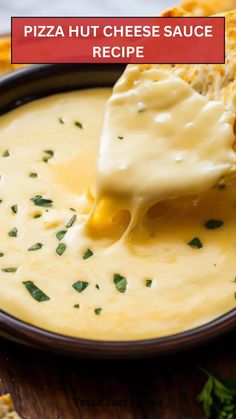 a piece of pizza hut cheese sauce being dipped into a bowl filled with cheesy bread