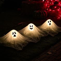 three lighted ghost decorations sitting on the ground