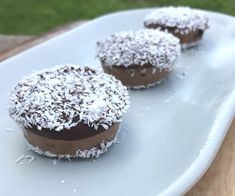 three chocolate desserts on a white plate covered in powdered sugar and sprinkles