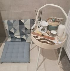 a table with various items on it next to a chair and pillow in the corner