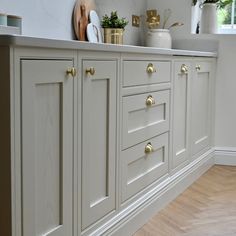 a kitchen with white cabinets and gold handles