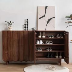 a wooden cabinet sitting next to a white rug and potted plant on top of a hard wood floor