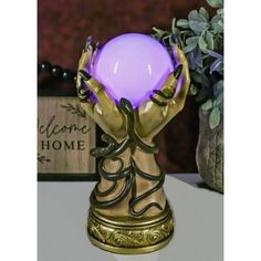 a purple light sitting on top of a table next to a vase with flowers in it