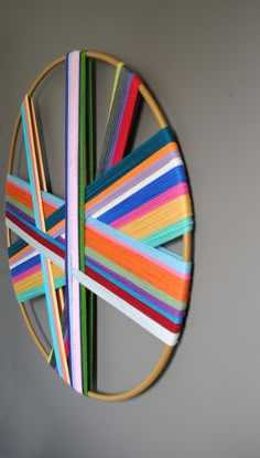 a multicolored circular object hanging on the wall in front of a gray wall