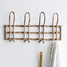 a towel rack made out of branches with hooks on the wall and clothes hanging from it