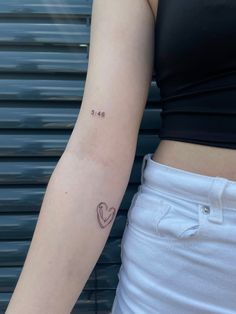 a woman's arm with a small heart tattoo on the left side of her right arm