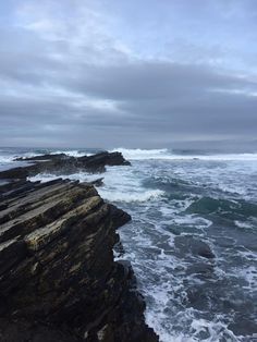 an ocean view with waves crashing on the rocks