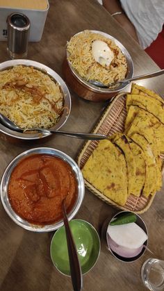 several different types of food sitting on a table with bowls and spoons next to each other