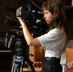 a woman holding a camera in front of a recording equipment set up on a tripod