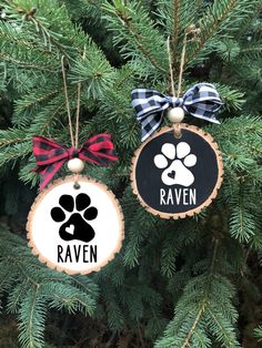 two ornaments hanging from a christmas tree decorated with dog paw prints and the name raven