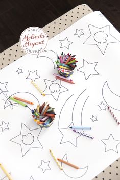 some crayons are laying on top of a white paper with stars and crescents