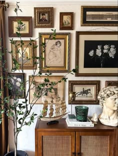 a living room with pictures on the wall and a vase filled with flowers in it