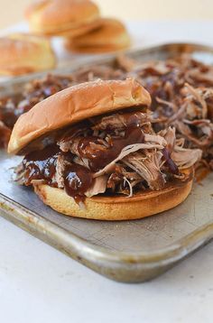 a pulled pork sandwich on a bun with barbecue sauce in the middle and some other pastries to the side