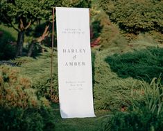 a white sign that says harley and amber in front of some bushes with trees behind it