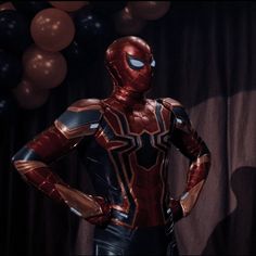 a man dressed as spider - man stands in front of balloons