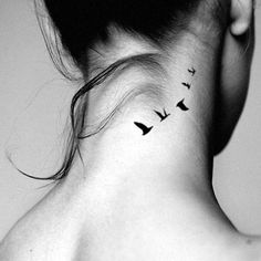 a woman's neck tattoo with birds on her left side and behind the neck