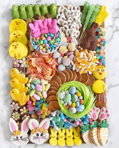 an assortment of cookies and candies are arranged on a marble slab top with easter decorations