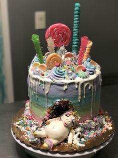 a birthday cake decorated with candy, candies and unicorn figurines on a table