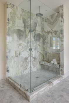 a bathroom with marbled walls and flooring, including a walk - in shower