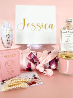 an assortment of personal care items on a pink table with a white box and gold lettering