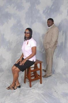 a man standing next to a woman sitting on a chair