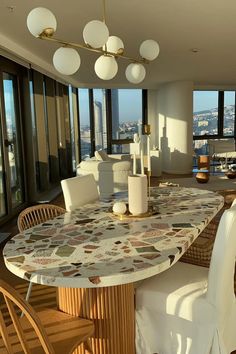 a dining room table and chairs in front of large windows overlooking the cityscape