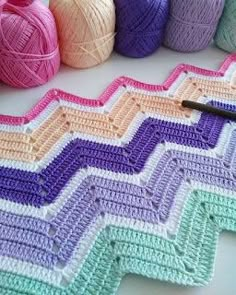 several balls of yarn sitting on top of a table next to crochet hooks