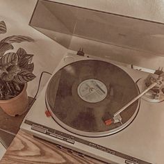 an old record player sitting on top of a table next to a potted plant