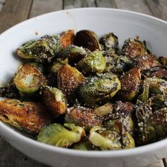 a white bowl filled with brussel sprouts on top of a wooden table