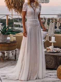 a woman standing on top of a roof wearing a white dress with sheer lace detailing