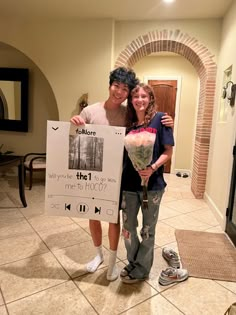 two people standing next to each other holding a sign