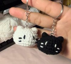 a hand holding two crocheted key chains in front of a ball of yarn