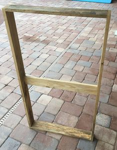 a wooden frame sitting on top of a brick sidewalk