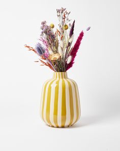 a yellow and white striped vase with flowers in it