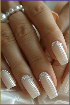 a woman's hands with white and silver nail polishes on her nails, holding pearls