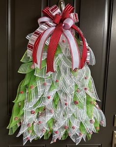 a christmas tree shaped door hanger with red, white and green ribbons on it