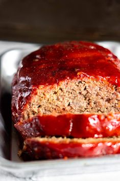 sliced meatloaf in a metal pan with ketchup on top