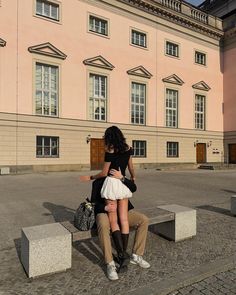 two people sitting on a bench in front of a building