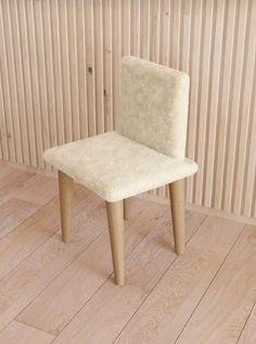 a white chair sitting on top of a hard wood floor next to a wooden wall