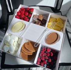 an open lunch box filled with fruit, crackers and other snacks on a chair