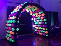 an arch made out of balloons in the middle of a room with lights on it