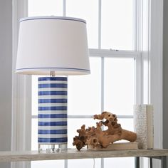 a blue and white lamp sitting on top of a wooden shelf next to a window