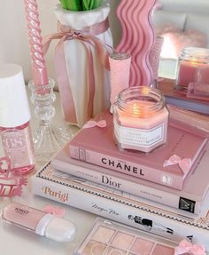 a table topped with books and candles next to vases filled with pink tulips